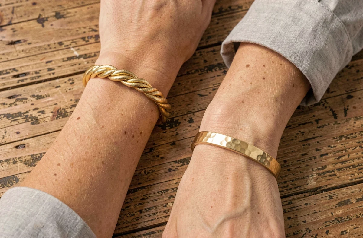 Comparaison de deux bracelets femme en or aux finitions différentes, tressé et martelé, posés côte à côte sur bois